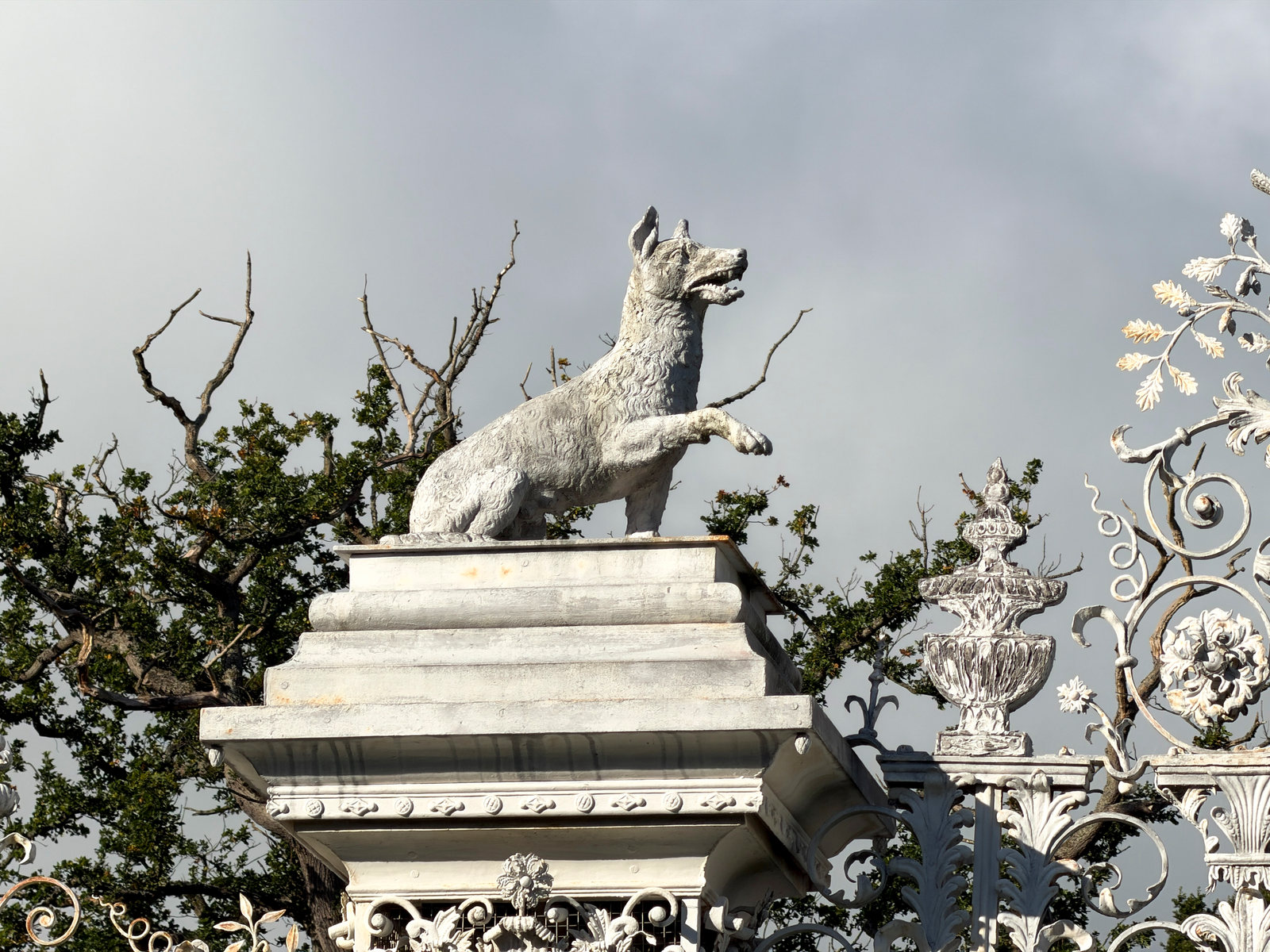 An animal sculpture above the elaborate iron entrance gates.